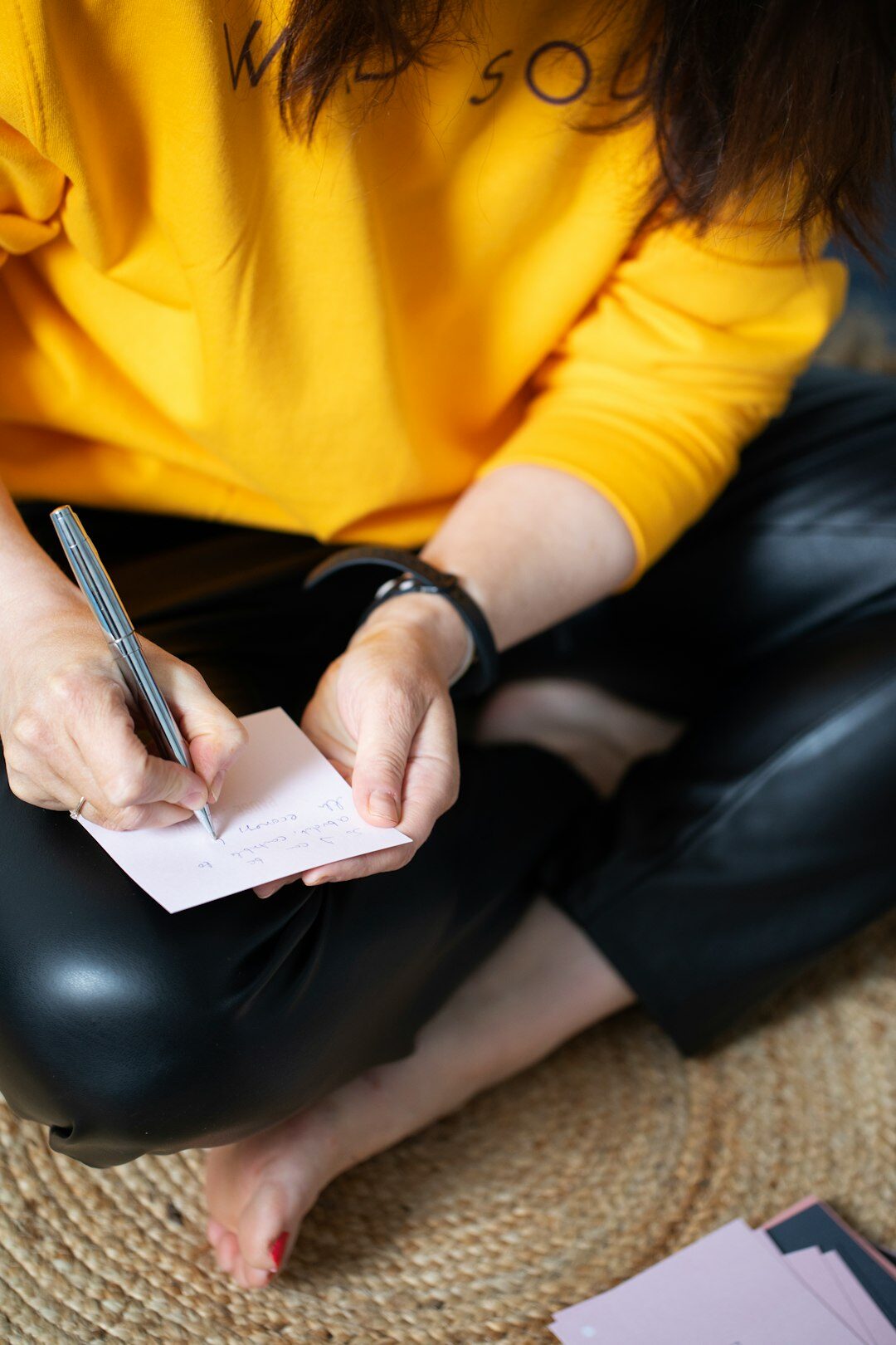 Brazilian woman writing in a journal at a sunlit desk reflecting on personal goals